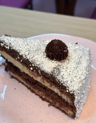 Fatia de bolo de chocolate com cobertura branca e brigadeiro